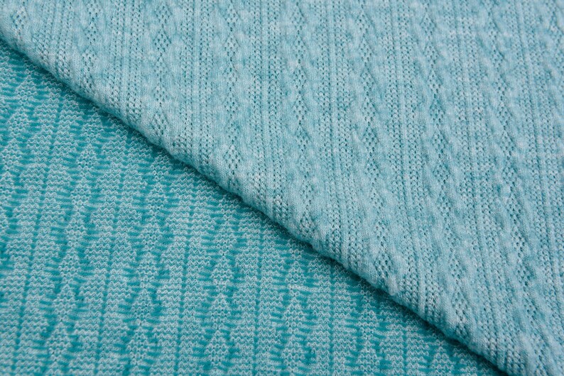 May include: Two pieces of teal blue knitted fabric with different patterns. The top piece has a cable knit pattern and the bottom piece has a chevron pattern.