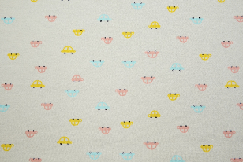 Op de afbeelding: Een witte stof met een herhalend patroon van kleine, kleurrijke auto's. De auto's zijn geel, blauw en roze.