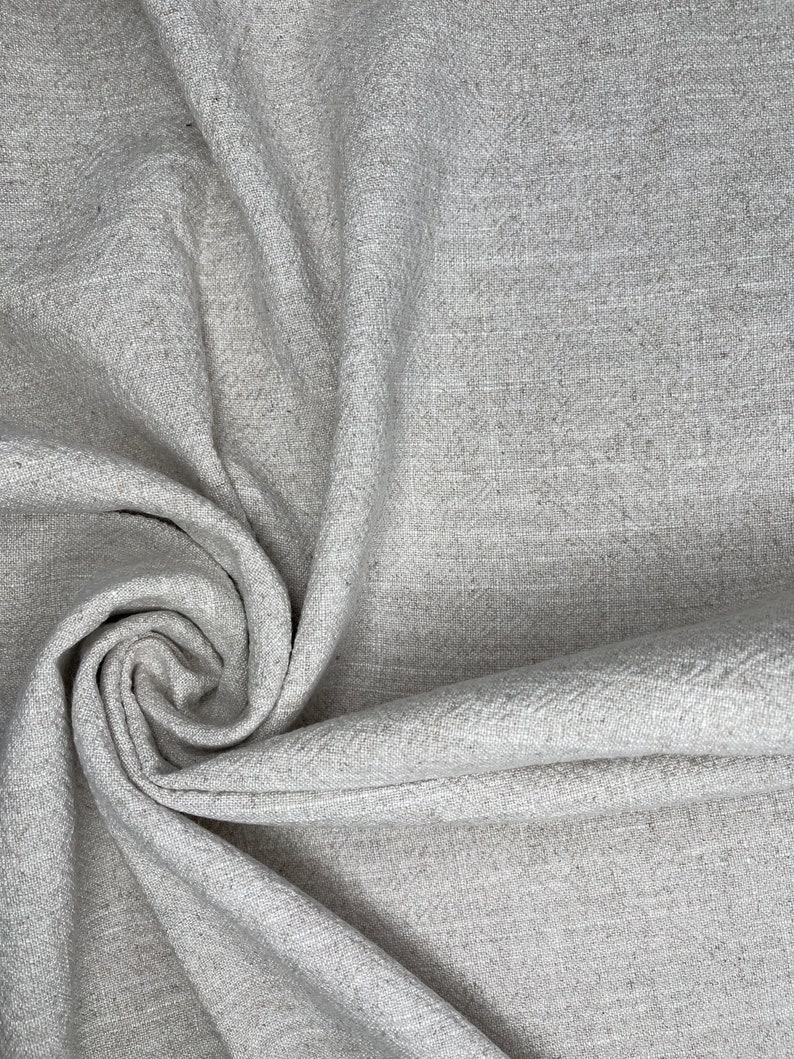 May include: A close-up of a gray fabric with a textured weave. The fabric is folded and draped, creating a soft, flowing look.