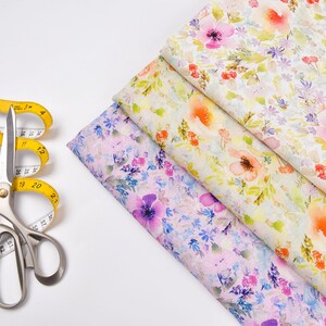 Peut inclure: Un ruban &agrave; mesurer jaune et des ciseaux argent&eacute;s sur une surface blanche, &agrave; c&ocirc;t&eacute; de trois morceaux de tissu avec des motifs floraux dans des tons de rose, jaune et blanc.