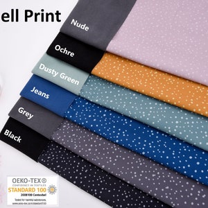 Peut inclure: Gros plan sur une pile de huit échantillons de tissu softshell de différentes couleurs avec un imprimé de pois blancs. Les couleurs sont nude, ocre, vert poussiéreux, jean, gris et noir. Le tissu est certifié Oeko-Tex Standard 100.