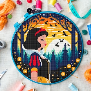 May include: A cross-stitch embroidery hoop depicting Snow White in a forest scene. The design features a blue hoop, black hair, a red bow, and a yellow and orange sunset. Sewing supplies such as thread, buttons, and scissors surround the hoop.