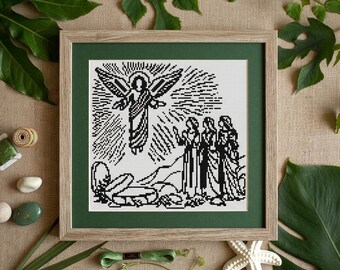May include: A framed cross-stitch embroidery featuring a black and white design of an angel appearing to three figures near an open tomb. The artwork is set within a light wood frame with a dark green mat, showcasing a detailed religious scene.