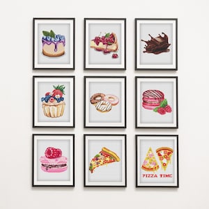 Op de afbeelding: Negen ingelijste kunstdrukken met aquarel illustraties van desserts. De prints tonen een blueberry cheesecake, een stukje kersencheesecake, een chocoladespat, een cupcake, donuts, macarons, een frambozenmacaron, een pizzapunt en twee pizzapunten met de tekst "PIZZA TIME".
