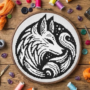 May include: A black and white cross-stitch embroidery of a wolf's head in a wooden hoop. The design features a detailed, stylized wolf with swirling patterns. The background is white, and the hoop is surrounded by sewing supplies.