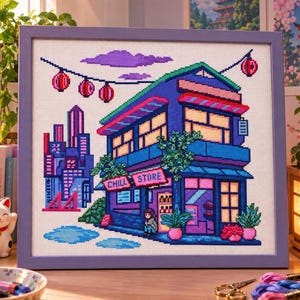 Peut inclure: Une broderie au point de croix encadrée représentant un bâtiment à deux étages avec l'inscription CHILL STORE en lettres néon roses. La scène inclut une ligne d'horizon urbaine, des lanternes rouges suspendues et des nuages violets.
