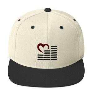 May include: A beige and black baseball cap with a red heart and black sound wave graphic. The cap has a flat brim and a curved crown.