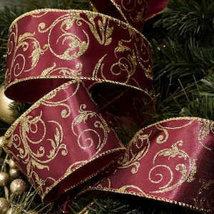 May include: Close-up of a burgundy ribbon with a gold, swirling pattern. The ribbon is thick and has a satin finish. The edges are trimmed with gold. The ribbon is used for holiday decorations.