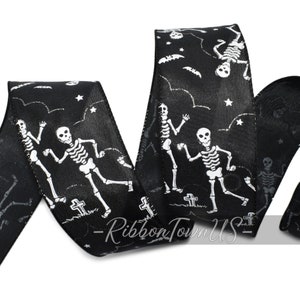 May include: Black Halloween ribbon featuring white skeletons, bats, stars, and tombstones. The ribbon has a glossy finish and is suitable for crafting and decorating. The design is repeated across the ribbon.