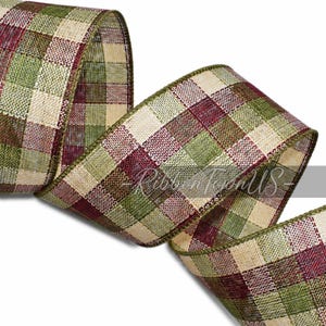 May include: A roll of decorative ribbon with a plaid pattern in shades of green, burgundy, and beige. The ribbon has a woven texture and a green border. The text "RibbonTownUS" is visible on the ribbon.