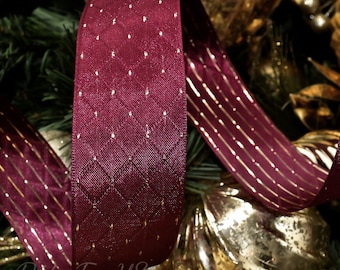 May include: Burgundy ribbon with a diamond pattern and gold accents. The ribbon is thick and has a textured appearance. Another section of the ribbon has gold vertical stripes. The background includes Christmas ornaments and greenery.