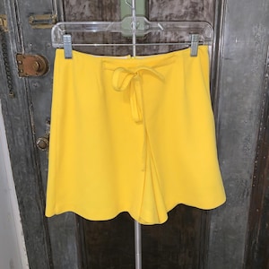 May include: A bright yellow pair of shorts with a tie at the waist.
