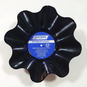 May include: A black vinyl record shaped into a bowl. The record label is blue and white and says "LONDON STEREOPHONIC" and "MORE HOT ROCKS (Big Hits & Faced Cookies)"  The Rolling Stones.
