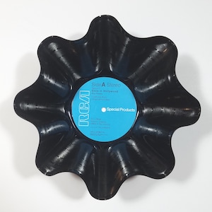 May include: A black, star-shaped bowl made from a repurposed vinyl record. The center label is light blue with white text, reading "Side A Stereo" and "Elvis in Hollywood." The RCA logo is visible. A unique decorative piece.