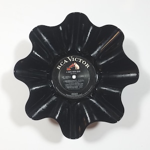 May include: A black, upcycled vinyl record bowl with a scalloped edge. The center label reads "RCA Victor A Date With Elvis". The bowl is a unique decorative item, perfect for holding small items.