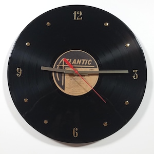 May include: A circular wall clock crafted from a black vinyl record featuring an Atlantic label with the text AC/DC For Those About To Rock We Salute You. The clock has gold-colored numerals at the 12, 3, 6, and 9 positions, silver hands, and a red second hand.