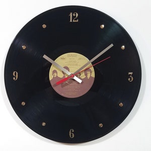 May include: Black vinyl record clock with gold numbers and a red second hand. The record is a Beatles album titled "Love Songs".