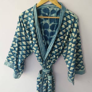 Op de afbeelding: Een blauwe en witte katoenen badjas met een strikceintuur. De badjas heeft een geometrisch ontwerp met een witte achtergrond en blauwe driehoeken.