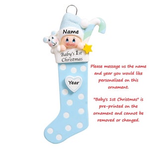 May include: Blue and white personalized Christmas stocking ornament with a baby boy wearing a Santa hat and holding a candy cane. The ornament has the text "Baby's 1st Christmas" and a space for a name and year.
