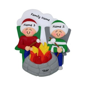 May include: A personalized Christmas ornament featuring two people sitting around a campfire with the text "Family Name", "Name 1", "Name 2", and "Year".