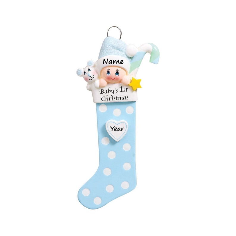 May include: Blue and white polka dot stocking ornament with a baby boy peeking out of the top. The stocking has a heart-shaped tag with the word "Year" on it. The stocking also has a tag that says "Baby's 1st Christmas" and a space for a name.