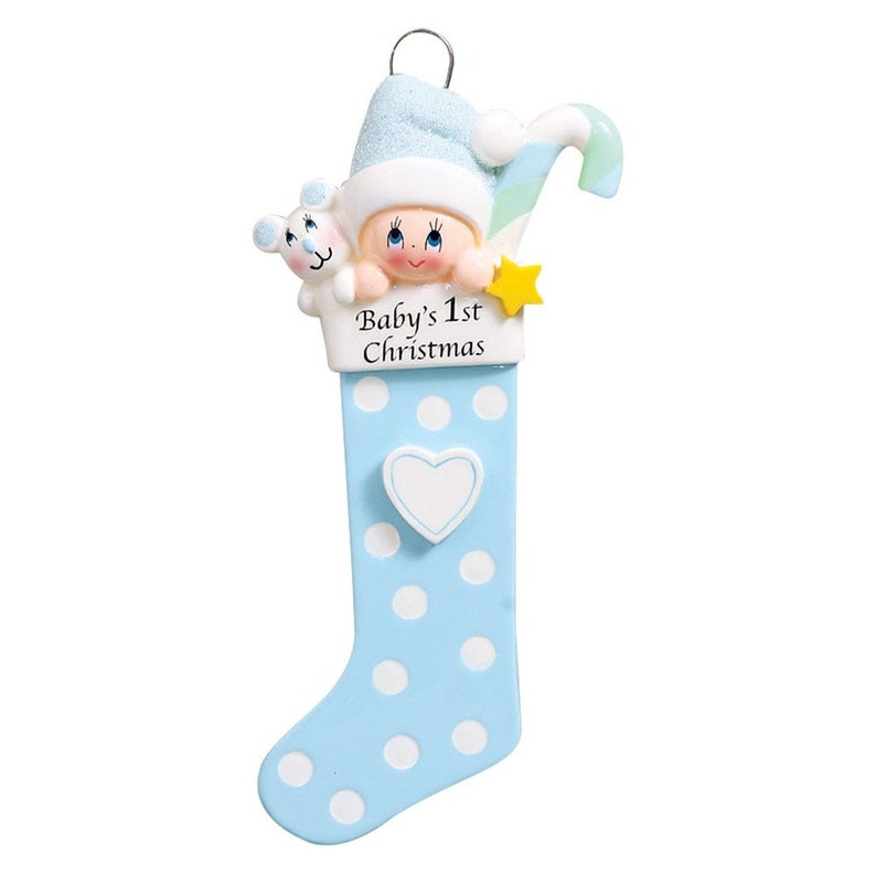 May include: Blue and white stocking ornament with a baby's face peeking out of the top. The stocking has white polka dots and a heart on the front. The text "Baby's 1st Christmas" is written on the stocking.