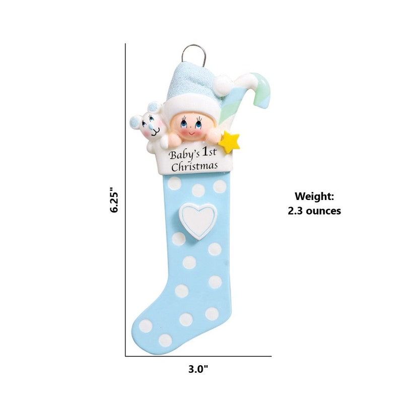 May include: Blue and white Christmas stocking ornament with a baby's face peeking out of the top. The stocking has white polka dots and a white heart on the side. The text "Baby's 1st Christmas" is printed on the stocking. The ornament is 6.25 inches tall and 3 inches wide and weighs 2.3 ounces.