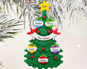 May include: A green glittery Christmas tree ornament featuring a yellow star at the top labelled Year, a white banner across the centre labelled The Millers, and five colourful baubles labelled Sophia, Henry, Liam, Olivia, and James.