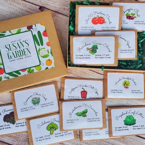 May include: A seed box labeled "Seeds for Susan's Garden" with various seed packets. The packets include varieties like heirloom tomatoes, Swiss chard, bell peppers, and lettuce. The box is brown with a colorful vegetable illustration.
