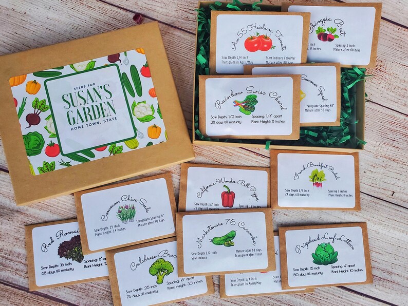 May include: A seed box labeled "Seeds for Susan's Garden" with various seed packets. The packets include varieties like heirloom tomatoes, Swiss chard, bell peppers, and lettuce. The box is brown with a colorful vegetable illustration.