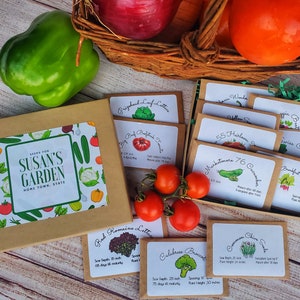 May include: A box set of garden seeds with a label that reads "Seeds for Susan's Garden". The set includes various seed packets for vegetables like tomatoes, lettuce, and cucumbers. Fresh produce, including tomatoes and a green bell pepper, are also in the image.