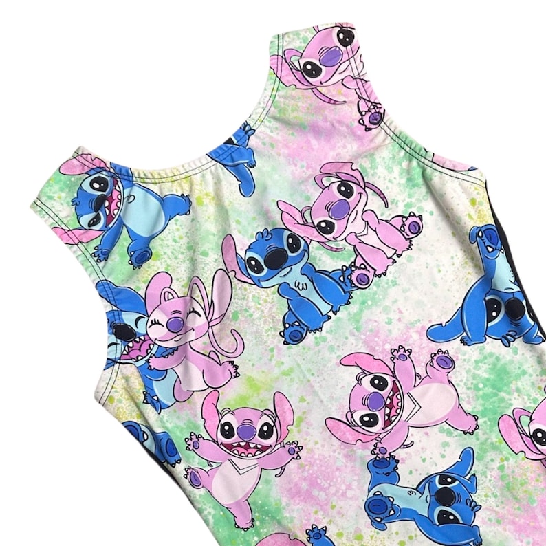 Puede incluir: Un leotardo blanco con un fondo de pintura salpicada de colores vivos que presenta un patr&oacute;n repetido de Stitch azul y personajes Angel rosa de la pel&iacute;cula de Disney Lilo & Stitch.