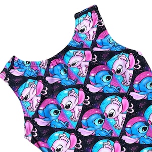 Könnte beinhalten: Ein ärmelloser Einteiler mit schwarzem Hintergrund und einem sich wiederholenden Muster aus blauen und rosa Comicfiguren in Herzen. Die Figuren sind vor einem galaktischen Hintergrund mit rosa und blauen Wirbeln platziert.