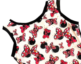 May include: A white sleeveless leotard with a black trim and a red and white polka dot bow pattern.