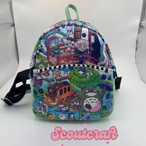 May include: A mini backpack featuring a colorful anime-style design with characters from various animated films. The backpack has a green trim, a top handle, and adjustable black straps. The word "Scoutcraft" is printed in pink script at the bottom.