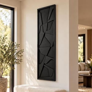 May include: A tall, rectangular wall art piece featuring a matte black frame and a geometric, three-dimensional abstract relief pattern composed of various overlapping black panels and angular shapes mounted on a matching black background.