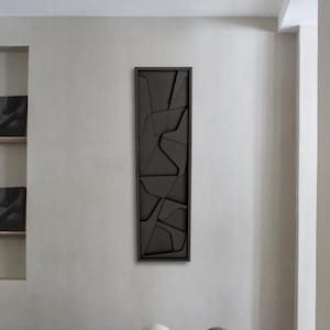 May include: A minimalist living room with a black framed abstract wall art piece and a collection of round, textured, gray and white balls on the floor.