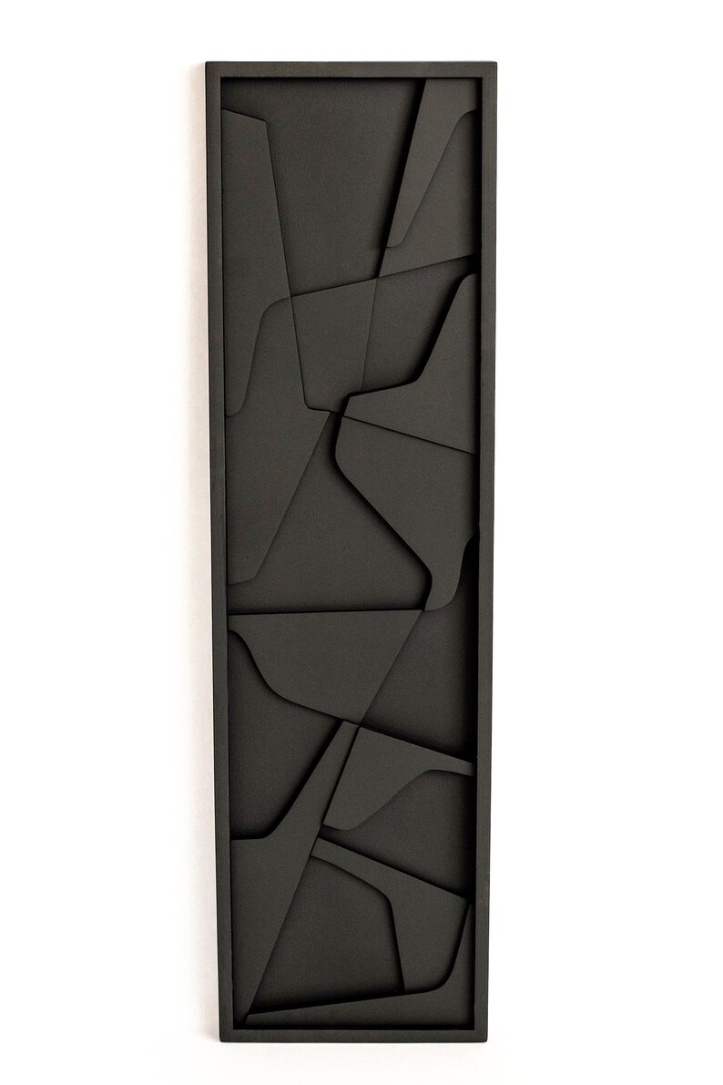 May include: Black wooden wall art with a geometric design. The art is made of multiple pieces of wood that are cut into different shapes and sizes. The wood is painted black and the pieces are arranged in a random pattern.
