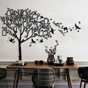 May include: Black wall art featuring a tree design with integrated photo frames and bird silhouettes. The tree's branches and leaves are intricately detailed. The frames are rectangular, and the birds are depicted in flight, ideal for home decor.