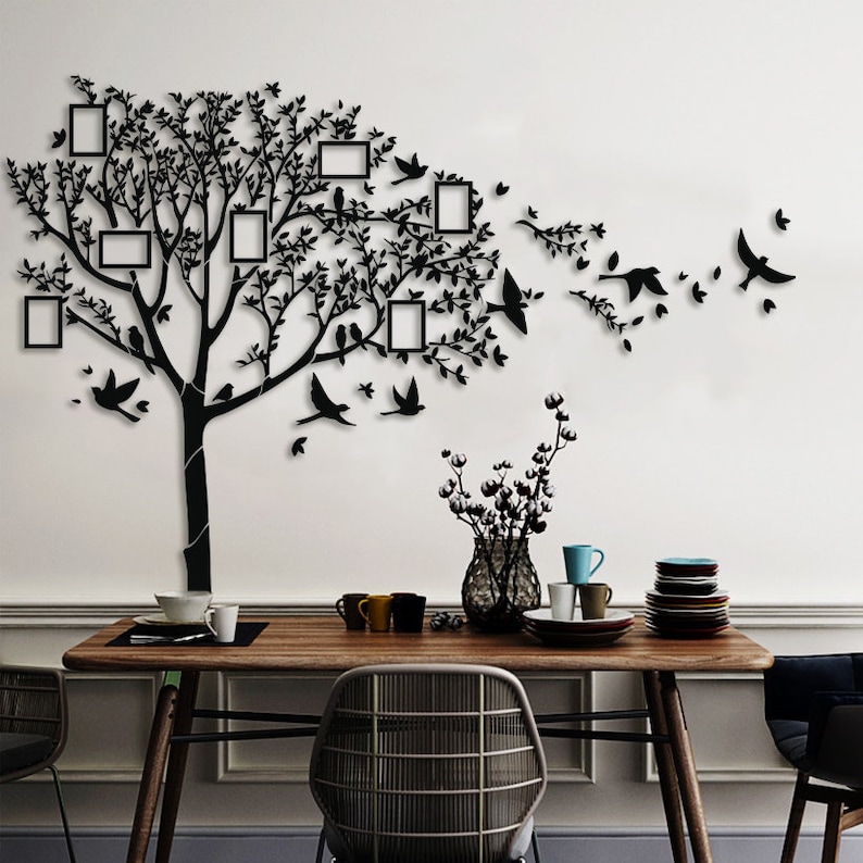 May include: Black wall art featuring a tree design with integrated photo frames and bird silhouettes. The tree's branches and leaves are intricately detailed. The frames are rectangular, and the birds are depicted in flight, ideal for home decor.