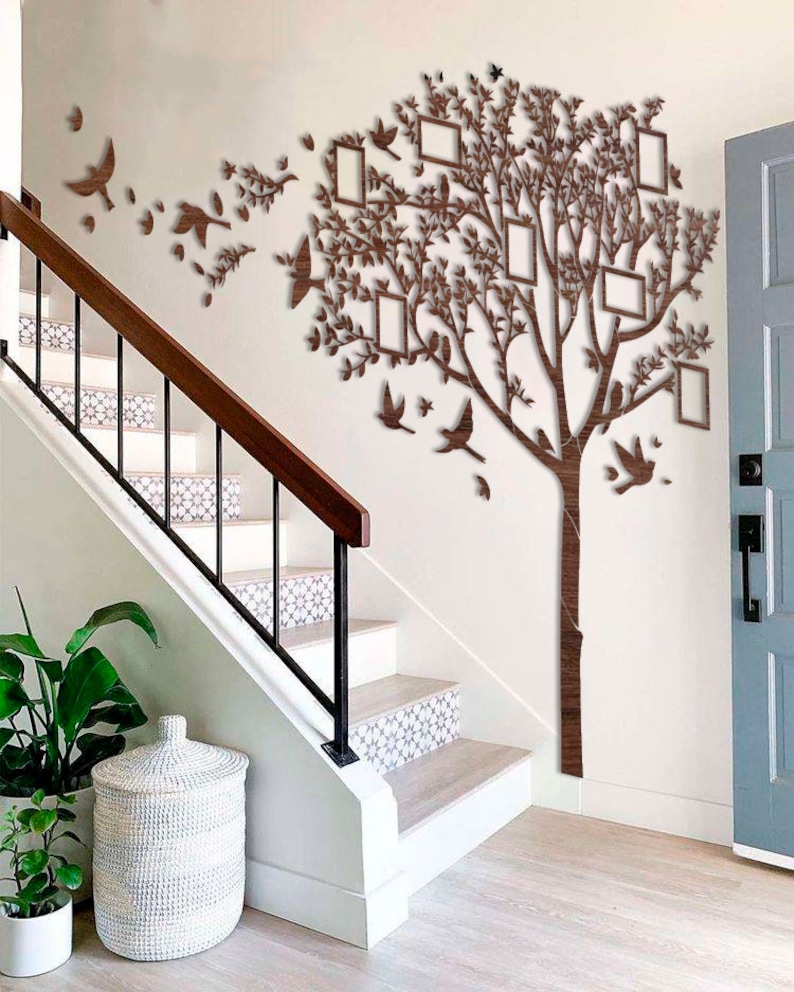 May include: A wooden wall decoration featuring a tree design with integrated photo frames and bird silhouettes. The brown tree has multiple rectangular frames for photos. Decorative birds are positioned around the tree, creating a wall art display.