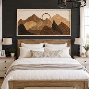 May include: A rectangular wall art piece featuring a layered wooden mountain landscape with a circular sun element, framed in light wood. The artwork displays various shades of brown and tan wood grain textures, mounted above a wooden bed frame.