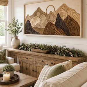 Puede incluir: Una pieza de arte mural rectangular de madera que presenta un paisaje monta&ntilde;oso tallado con un elemento solar circular. La obra muestra texturas en capas en tonos beige claro, marr&oacute;n medio y carb&oacute;n oscuro, enmarcada en madera clara.