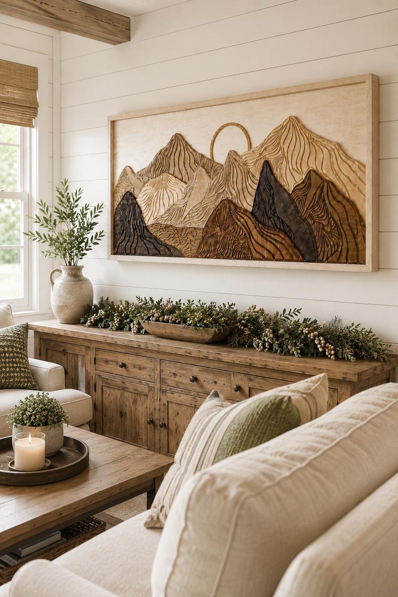 Puede incluir: Una pieza de arte mural rectangular de madera que presenta un paisaje monta&ntilde;oso tallado con un elemento solar circular. La obra muestra texturas en capas en tonos beige claro, marr&oacute;n medio y carb&oacute;n oscuro, enmarcada en madera clara.