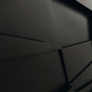 May include: Black wooden cabinet with geometric design and multiple drawers. The cabinet has a textured finish and is made of solid wood.