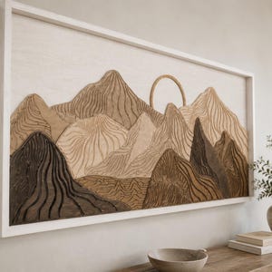 Puede incluir: Una pieza de arte mural rectangular que presenta un paisaje monta&ntilde;oso de madera en capas en tonos marr&oacute;n oscuro, marr&oacute;n claro y crema. El dise&ntilde;o incluye un elemento solar circular y texturas de l&iacute;neas talladas, todo dentro de un marco blanco.