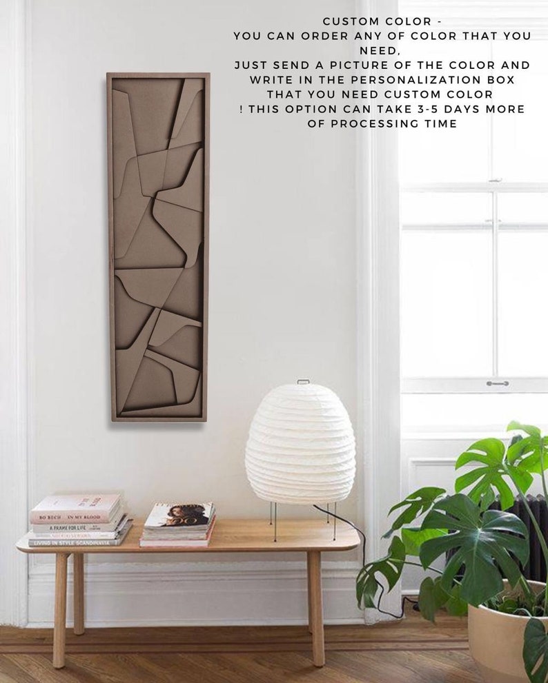 May include: A brown geometric wall art piece with a modern design. The art is hanging on a white wall above a wooden table with a white lamp and a green plant.