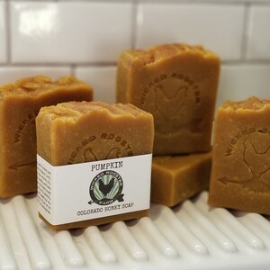 May include: Four bars of orange-brown soap with the text "Wicked Rooster Farm Colorado Honey Soap" and "Pumpkin" on the label. The soap features a rooster logo.
