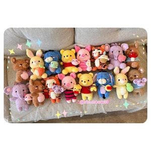 Pode incluir: Uma coleção de 17 animais de pelúcia de crochê, incluindo Winnie the Pooh, Tigger, Piglet, Eeyore e Rabbit. Os animais são todos de cores diferentes e têm expressões diferentes em seus rostos. Os animais de pelúcia estão sentados em um sofá branco e cinza.