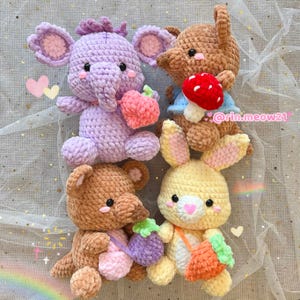 May include: Four crocheted stuffed toys: a purple elephant holding a pink strawberry, a brown bunny holding a red mushroom, a brown kangaroo holding a purple turnip, and a yellow bunny holding an orange carrot. The stuffed toys are all sitting on a white and blue background with a rainbow in the bottom left corner. #rin.meow21